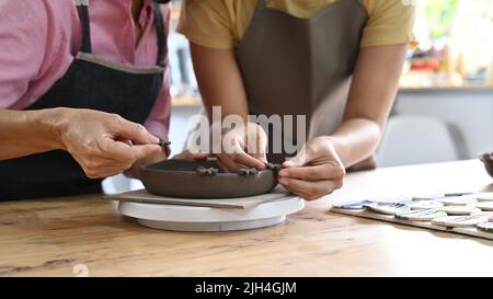 Kurzer Schuss junger Mann und reife Frau Herstellung und Dekoration Keramik in der Werkstatt Stockfoto