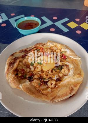 'roti sarang burung' oder Pratha sieht aus wie ein Vogelnest mit halb gekochten Eiern in der Mitte. Mit kleinen Garnelen hinzugefügt. Stockfoto