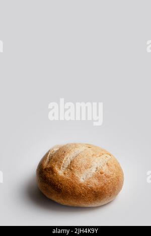 Runder Laib Weizenbrot auf Sauerteig auf hellem Hintergrund, vertikaler Rahmen mit Platz für Text. Stockfoto