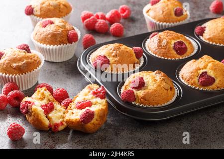 Süße Himbeer-Muffins mit weißer Schokolade in einer Muffin-Pfanne auf dem Tisch. Horizontal Stockfoto