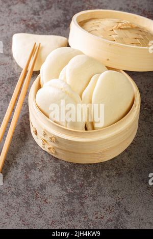 Gua bao, gedämpfte Brötchen in Bambus-Nahaufnahme, bao-Brötchen auf dem Tisch. Vertikal Stockfoto