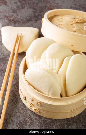 Nahaufnahme gedämpfter Bao-Buns auf dem Bambuskorb auf dem Tisch. Vertikal Stockfoto