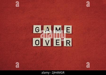 „Game Over“-Satz aus Holzfliesen mit Buchstaben auf rotem Hintergrund Stockfoto