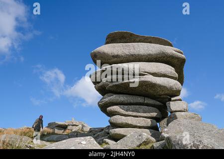 Ein Spaziergänger neben dem hoch aufragenden Granitfelsen stapelt den Cheesewring, der von Gletscheraktionen auf Stowes Hill auf Bodmin Moor in Cornwall verlassen wurde. Stockfoto