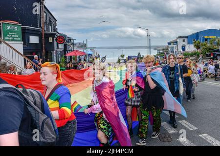 Das riesige farbenfrohe Banner, das von den Teilnehmern der Cornwall Prides Pride Parade im Zentrum von Newquay in Großbritannien getragen wurde. Stockfoto