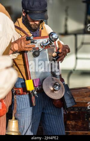 Ein Musiker, der das Waschbrett und andere Percussion Hooter und Glocken von den Old Time Matrosen spielt, die im Newquay Orchard Amphitheater in Cor auftreten Stockfoto