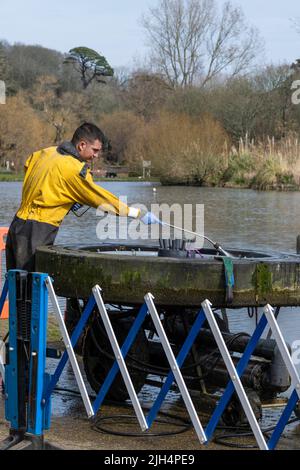 Ein Arbeiter, der einen Hochdruckreiniger verwendet und Wartungsarbeiten an einem Brunnen am Trenance Boating Lake in Newquay in Cornwall in Großbritannien durchführt. Stockfoto