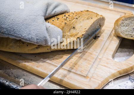 Frische verschiedene Brotscheibe und Schneidemesser auf Holztisch Hand Nahaufnahme Stockfoto