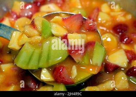 Eine Schale Obstsalat aus Scheiben von Bananen, Erdbeere, Cantaloupe, Äpfel und Saft von Mango und Orange gemischt, selektive Fokus eines Fr. Stockfoto