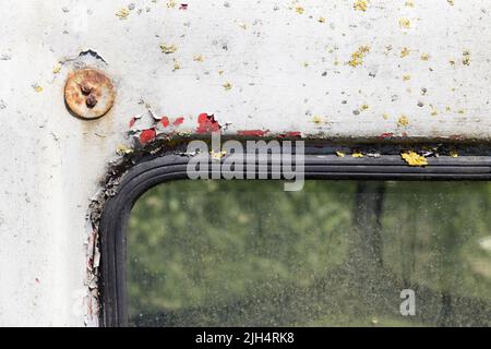 Verwitterte graue, rote und gelbe Farbe mit gelber Flechte auf einem alten LKW-Fahrerhaus aus Metall Stockfoto