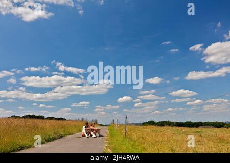Zwei junge Frauen, die auf einer Landstraße sitzen, Deutschland, Nordrhein-Westfalen, Sauerland Stockfoto