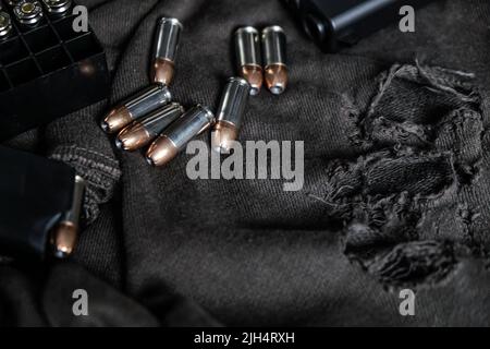 9mm verbergen halbautomatische Pistole mit Jacke heiligen Punkt Kugel auf Stoff Hintergrund Stockfoto