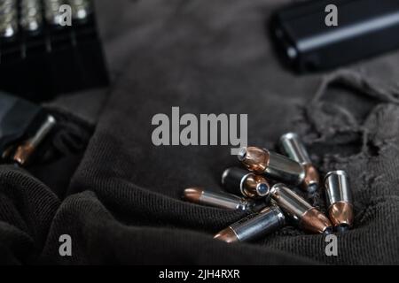 9mm verbergen halbautomatische Pistole mit Jacke heiligen Punkt Kugel auf Stoff Hintergrund Stockfoto