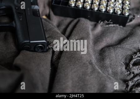 9mm verbergen halbautomatische Pistole mit Jacke heiligen Punkt Kugel auf Stoff Hintergrund Stockfoto