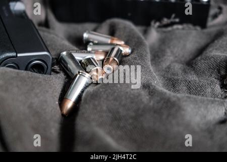 9mm verbergen halbautomatische Pistole mit Jacke heiligen Punkt Kugel auf Stoff Hintergrund Stockfoto