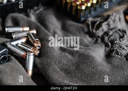 9mm verbergen halbautomatische Pistole mit Jacke heiligen Punkt Kugel auf Stoff Hintergrund Stockfoto