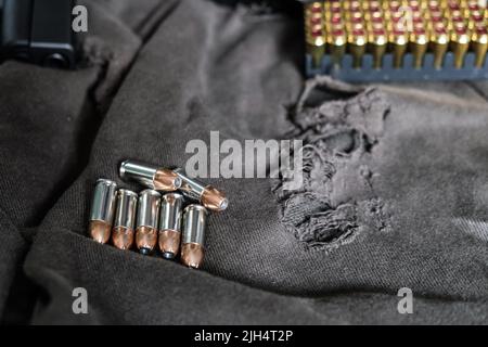 9mm verbergen halbautomatische Pistole mit Jacke heiligen Punkt Kugel auf Stoff Hintergrund Stockfoto