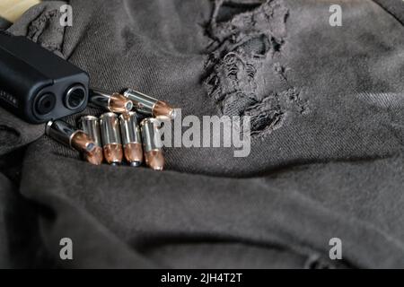 9mm verbergen halbautomatische Pistole mit Jacke heiligen Punkt Kugel auf Stoff Hintergrund Stockfoto