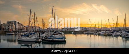 Atardecer en el puerto deportivo de Gijón, con los colores de los reflejos en el agua de los barcos, edificios y cielo, Asturias España Stockfoto