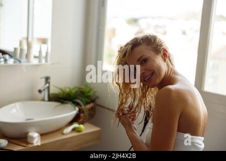 Glückliche junge schöne weibliche Trocknung nasses Haar im Bad und lachen. Nach dem Duschen. Stockfoto