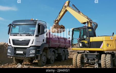 Bagger belädt LKW mit Aushub Stockfoto