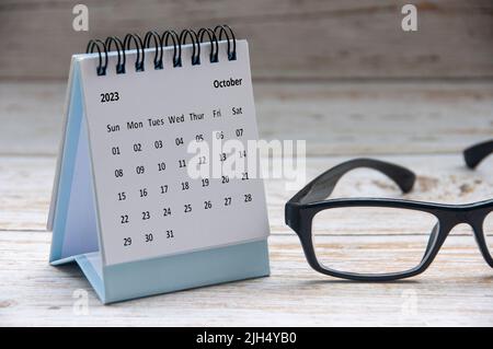 Oktober 2023 weißer Tischkalender auf Holztisch mit Glasergrund. Speicherplatz kopieren Stockfoto