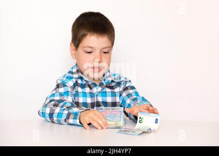 Ein 4-jähriger Junge zählt Geld, hält Euro in den Händen. Unterweisung von Kindern in finanzieller Bildung, Taschengeld. Stockfoto