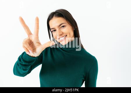 Happy Brunette Mädchen, zählen drei, zeigt Finger, lächelnd, im weißen Studio stehen Stockfoto