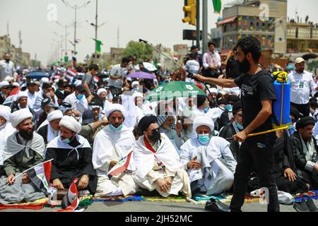 Bagdad, Irak. 15.. Juli 2022. Anhänger des irakischen schiitischen Geistlichen Muqtada al-Sadr, Anführer der Sadrist-Bewegung, versammeln sich auf den Straßen, um das wöchentliche muslimische Freitagsgebet auf den Ruf ihres Führers zu verrichten. Quelle: Ameer Al-Mohammedawi/dpa/Alamy Live News Stockfoto