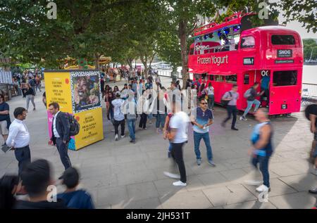 London, England, Großbritannien - 21 2019. Juli: Besucher spazieren am Ufer der Themse entlang und sehen sich Neuheiten an, darunter einen pinkfarbenen Londoner Bus. Stockfoto