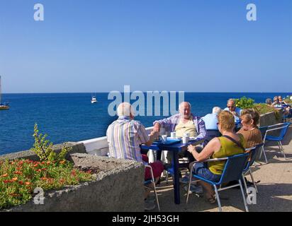 Senioren, ältere Menschen, die an der Uferpromenade sitzen, Arguineguin, Grand Canary, Kanarische Inseln, Spanien, Europa Stockfoto