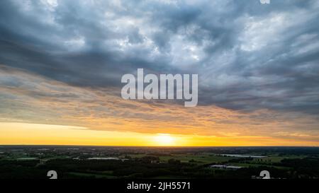 Luftaufnahme erstaunlicher Sonnenuntergang über den Vororten mit der Stadt unter dramatischer Regenwolke. Globaler Erwärmungs-Effekt Schwarzes Gewitter dramatische Regenwolken, dramatischer Himmel, von einer Drohne geschossen. Hochwertige Fotos Stockfoto