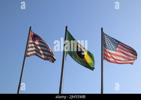 Schwenken Sie farbenfrohe Flaggen von Sao Paulo, Brasilien und den Vereinigten Staaten gegen den blauen Himmel. Stockfoto