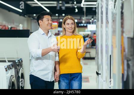 Glückliche asiatische Paar Familie Mann und Frau treffen die Wahl der neuen Haushaltsgeräte in Supermarkt Umfrage Kühlschrank Kühlschrank Kühlraum, frieren Stockfoto