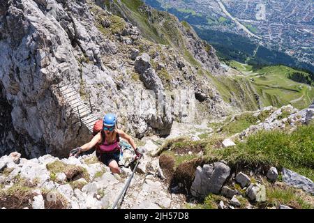 Weibliche Touristin auf exponierten Bergrücken oberhalb von Innsbruck, dem Nordkette klettersteig in Österreich. Holzbrücke, aktiv, Bergsteigen. Stockfoto