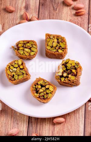 Pistazien-Kadayif-Dessert. Kadayif Baklava mit Pistazien-Füllung auf einem Holzboden. Türkische Küche, Desserts. Nahaufnahme. Lokaler Name fıstıklı kadayif Stockfoto