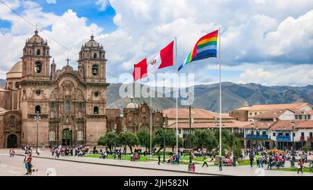 Cusco, Peru.Feb 5, 2017: Peruanische und Tahuantinsuyo Flagge auf dem Hauptplatz von Cusco, Peru mit der Kirche der Gesellschaft Jesu im Hintergrund. Stockfoto