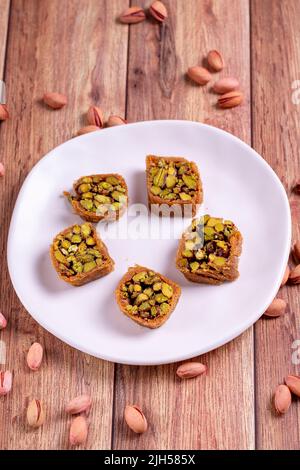 Pistazien-Kadayif-Dessert. Kadayif Baklava mit Pistazien-Füllung auf einem Holzboden. Türkische Küche, Desserts. Nahaufnahme. Lokaler Name fıstıklı kadayif Stockfoto