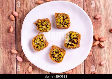 Pistazien-Kadayif-Dessert. Kadayif Baklava mit Pistazien-Füllung auf einem Holzboden. Türkische Küche, Desserts. Nahaufnahme. Lokaler Name fıstıklı kadayif Stockfoto