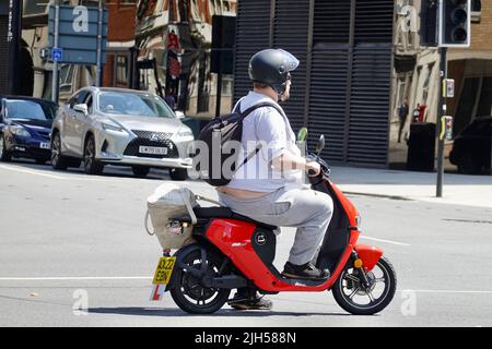 Ipswich, Suffolk, Großbritannien - 15. Juli 2022: Ein Motorroller-Fahrer wartet mitten auf die geschäftige Kreuzung Civic Drive. Stockfoto
