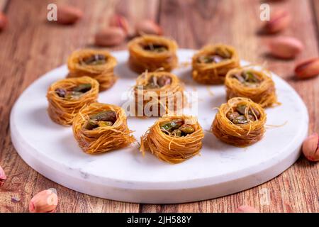 Bulbul Kadayif mit Pistazie. Kadayif Baklava mit Pistazien-Füllung auf einem Holzboden. Türkische Küche, Desserts. Nahaufnahme. Lokaler Name Antep Fıstıklı Stockfoto