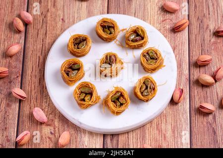 Bulbul Kadayif mit Pistazie. Kadayif Baklava mit Pistazien-Füllung auf einem Holzboden. Türkische Küche, Desserts. Nahaufnahme. Lokaler Name Antep Fıstıklı Stockfoto