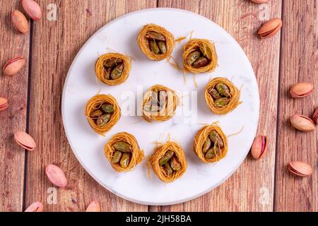 Bulbul Kadayif mit Pistazie. Kadayif Baklava mit Pistazien-Füllung auf einem Holzboden. Türkische Küche, Desserts. Nahaufnahme. Lokaler Name Antep Fıstıklı Stockfoto