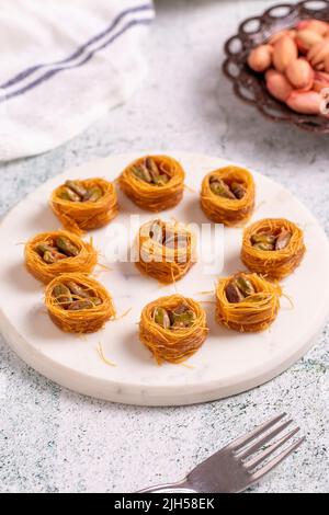 Bulbul Kadayif mit Pistazie. Kadayif Baklava mit Pistazien-Füllung auf einem Steinboden. Türkische Küche, Desserts. Nahaufnahme. Lokaler Name Antep Fıstıklı Stockfoto