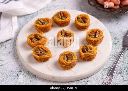 Bulbul Kadayif mit Pistazie. Kadayif Baklava mit Pistazien-Füllung auf einem Steinboden. Türkische Küche, Desserts. Nahaufnahme. Lokaler Name Antep Fıstıklı Stockfoto