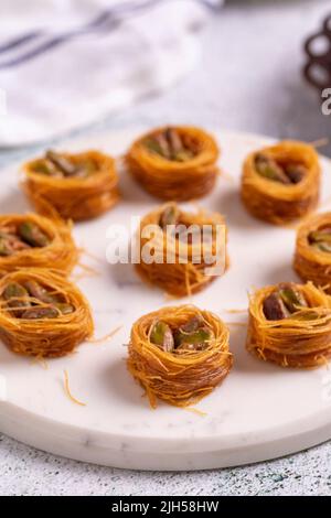 Bulbul Kadayif mit Pistazie. Kadayif Baklava mit Pistazien-Füllung auf einem Steinboden. Türkische Küche, Desserts. Nahaufnahme. Lokaler Name Antep Fıstıklı Stockfoto