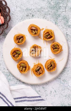 Bulbul Kadayif mit Pistazie. Kadayif Baklava mit Pistazien-Füllung auf einem Steinboden. Türkische Küche, Desserts. Nahaufnahme. Lokaler Name Antep Fıstıklı Stockfoto