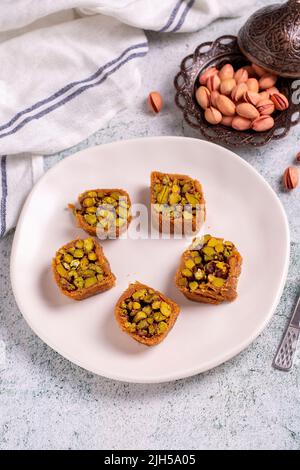 Pistazien-Kadayif-Dessert. Kadayif Baklava mit Pistazien-Füllung auf einem Steinboden. Türkische Küche, Desserts. Nahaufnahme. Lokaler Name fıstıklı kadayif Stockfoto