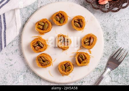 Bulbul Kadayif mit Pistazie. Kadayif Baklava mit Pistazien-Füllung auf einem Steinboden. Türkische Küche, Desserts. Nahaufnahme. Lokaler Name Antep Fıstıklı Stockfoto