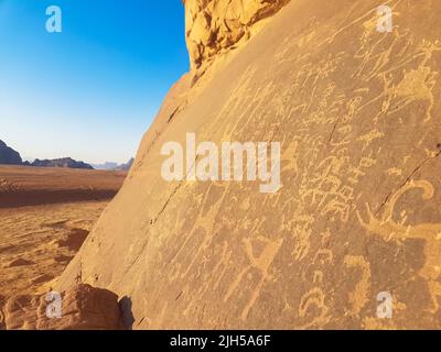 Sandsteinfelsen mit prähistorischer Kunst. Prähistorische Zivilisation hinterließ ihre primitiven Zeichnungen auf einer Kalksteinklippe in der Wadi Rum Wüste, Jordanien. Stockfoto